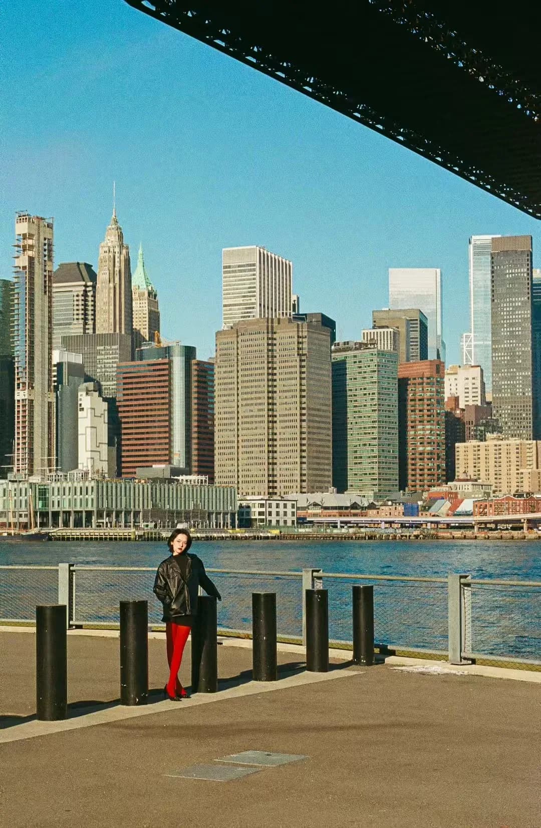 A waterfront figure beneath blue sky.