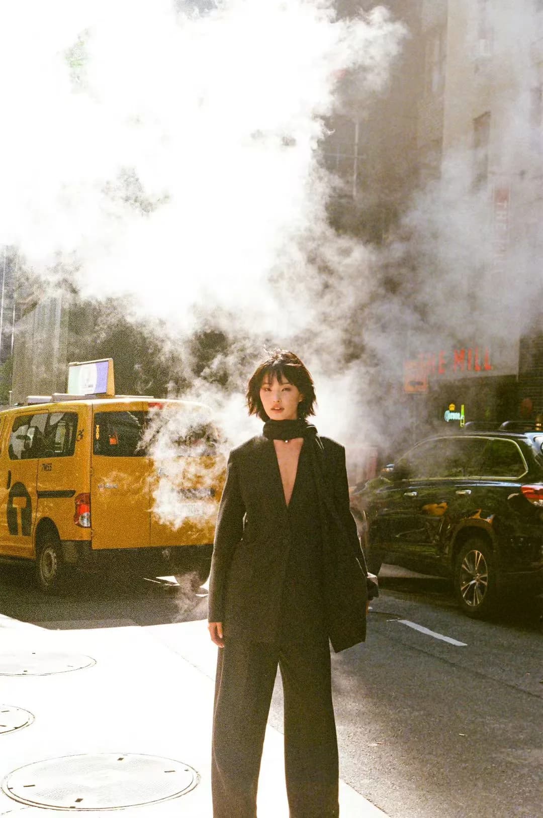 A dark suit framed by street steam.