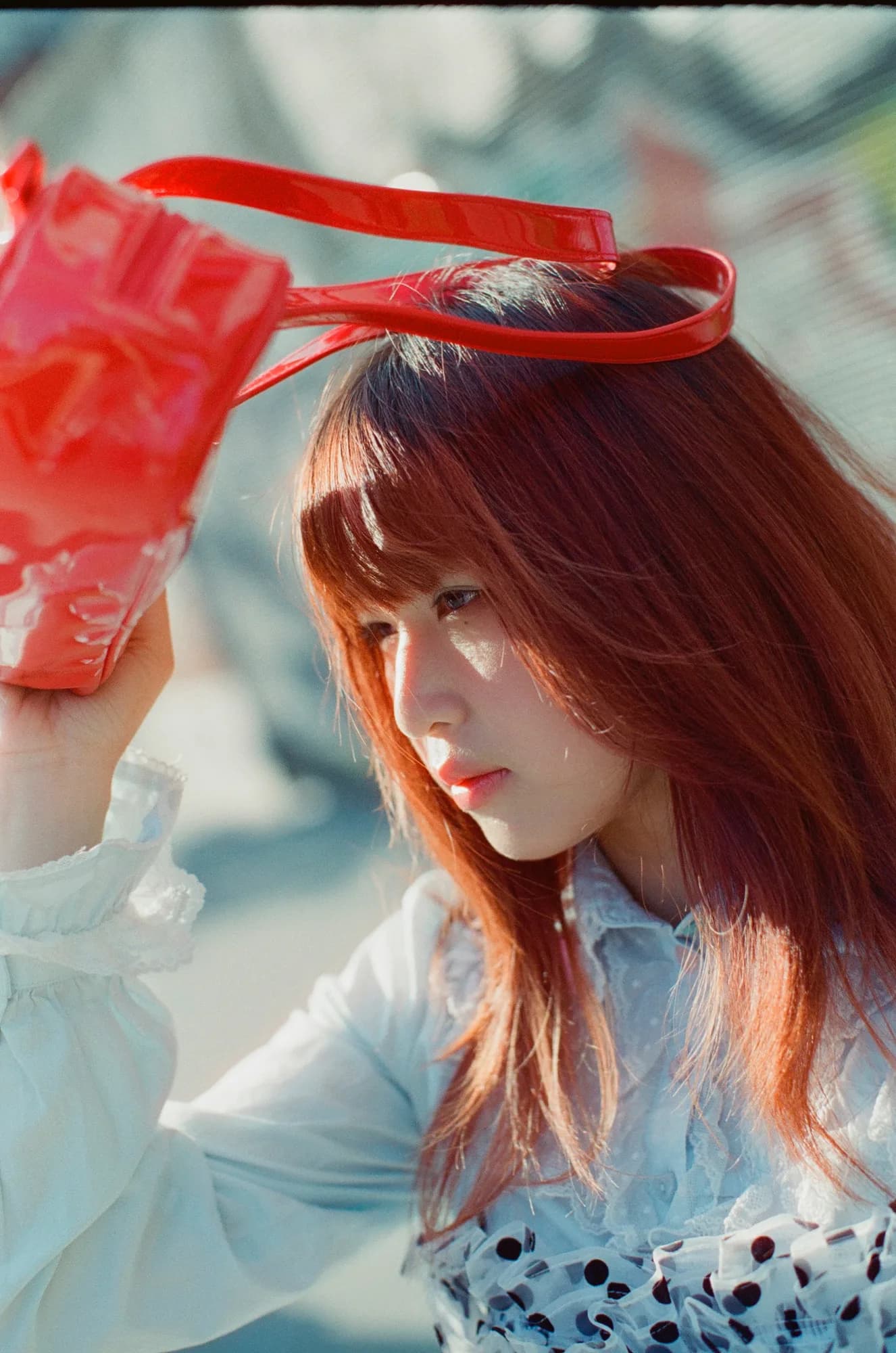 A red bag held above a portrait.