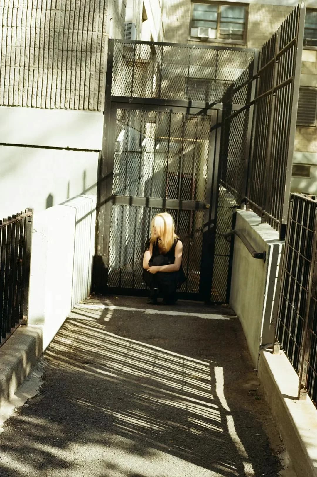A figure and shadows in a glass corridor.