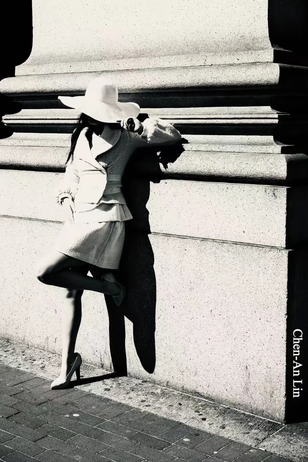 A monochrome figure and architectural shadows.