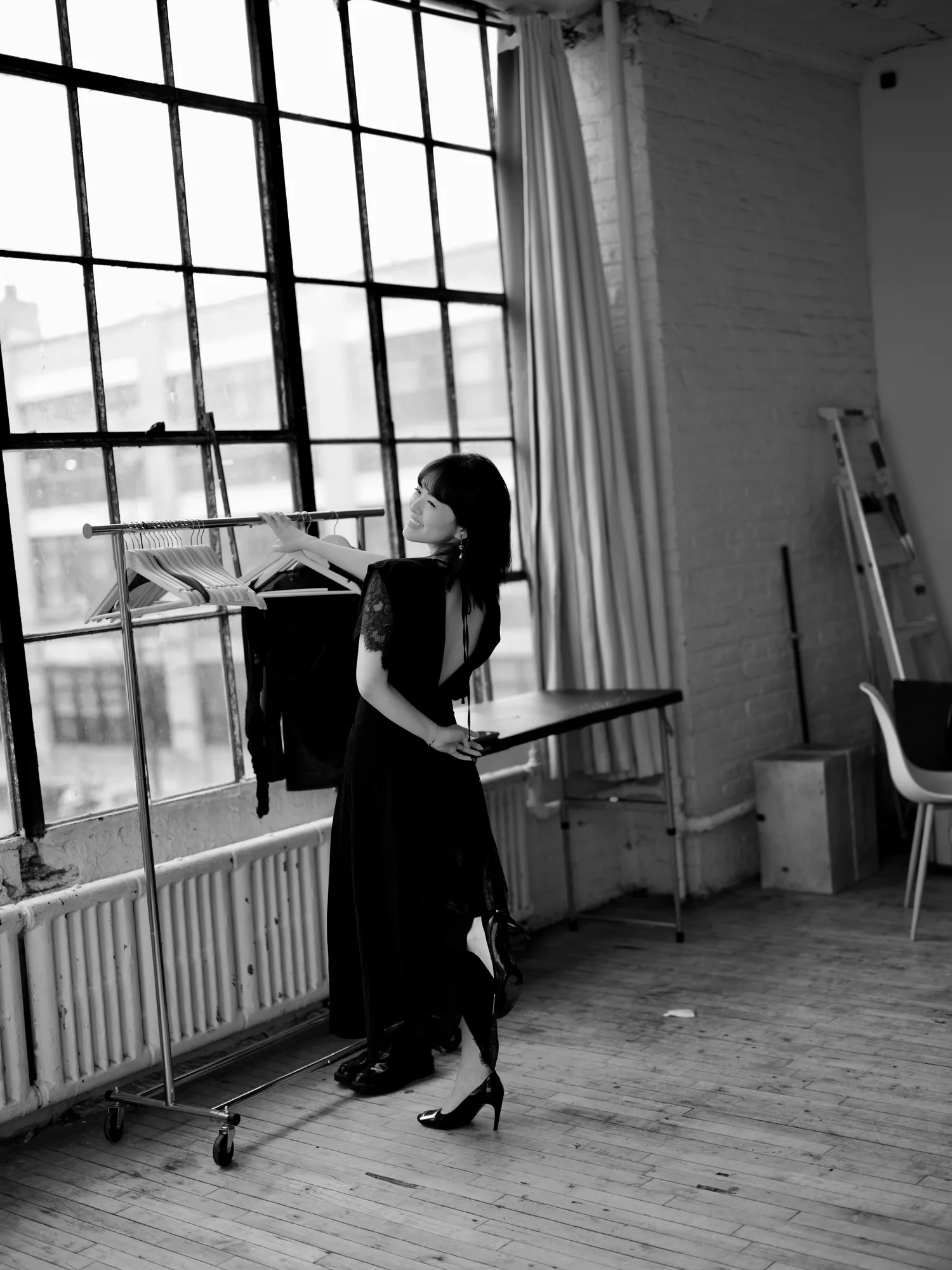 A monochrome figure beside a tall window.