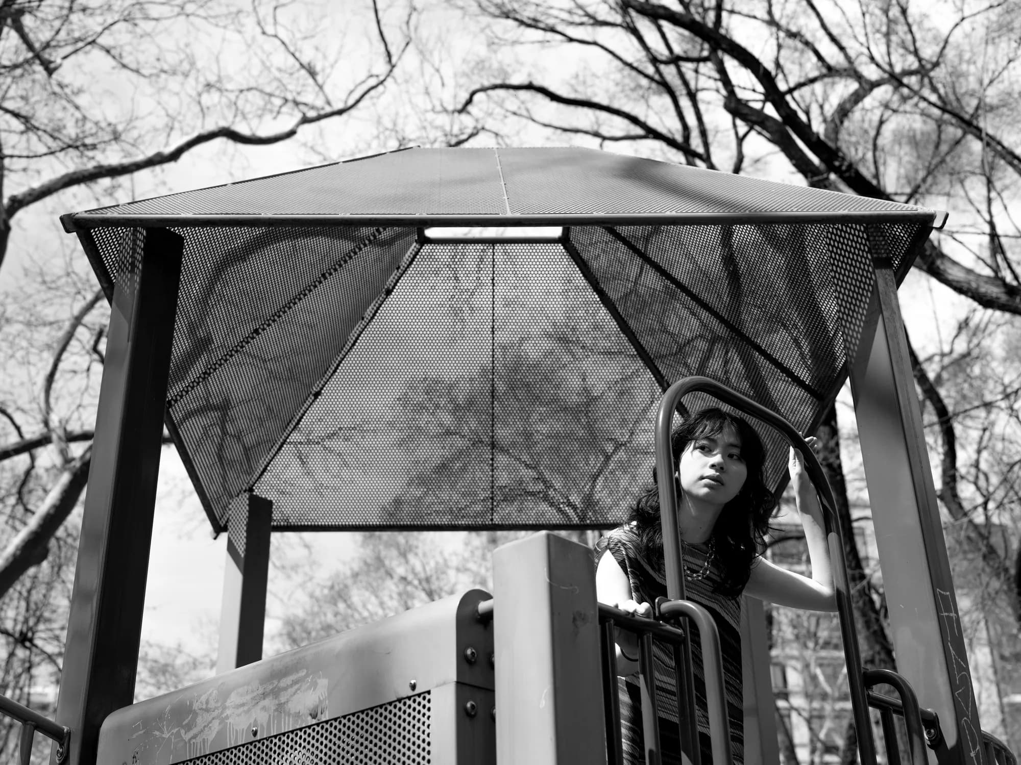 A monochrome figure beneath a glass shelter.
