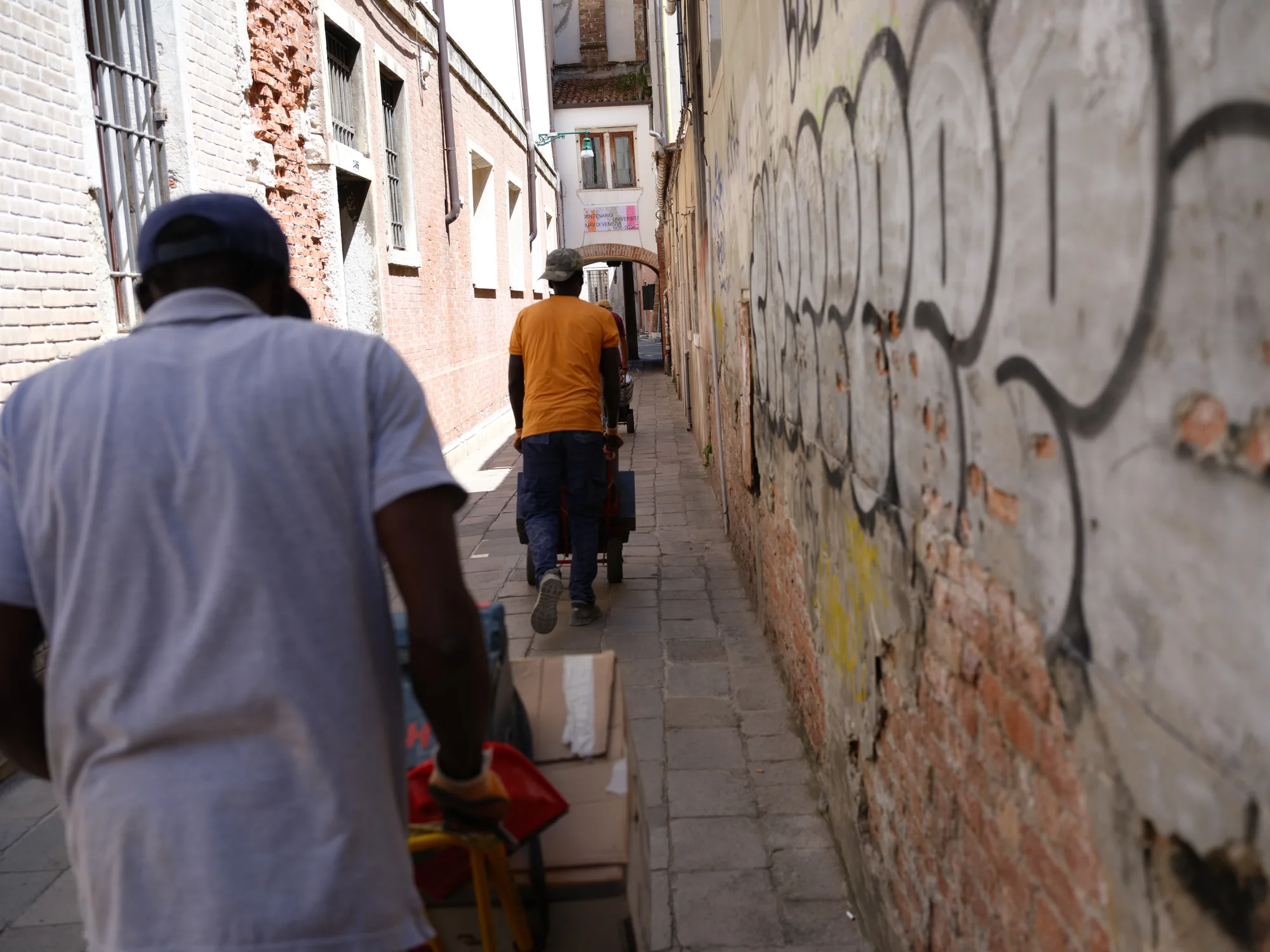 Figures walking through a warm narrow alley.