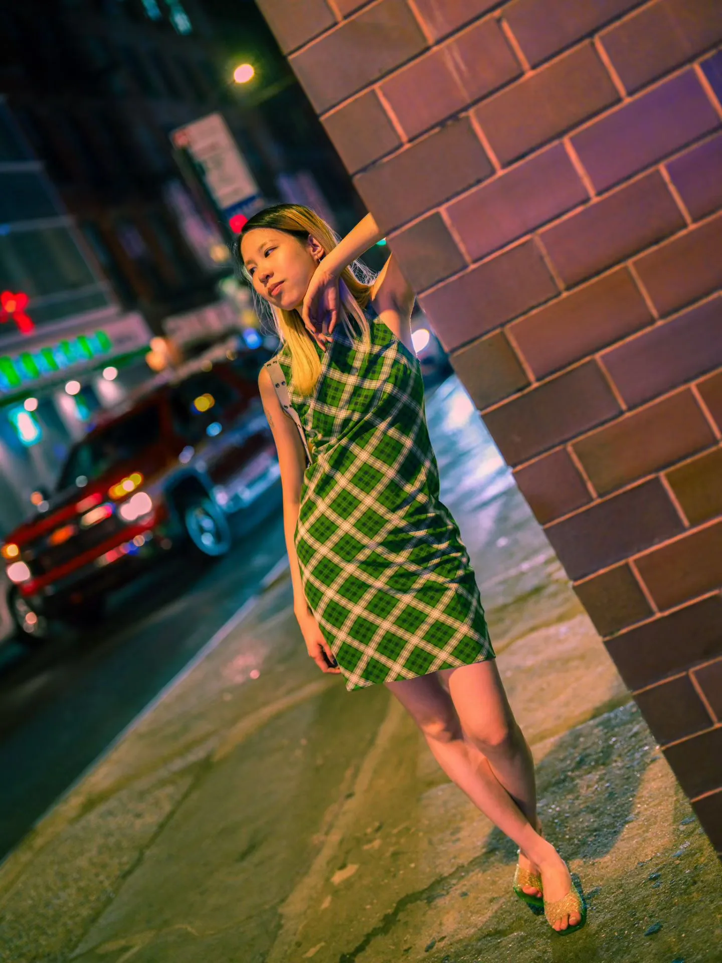A green checked dress against brick at night.