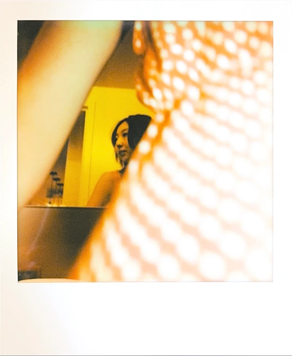 A portrait through a yellow patterned foreground.